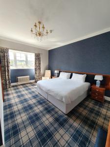 Un dormitorio con una gran cama blanca y una lámpara de araña. en The Glen Guesthouse en Selkirk