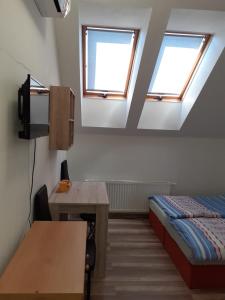 Habitación con 1 cama, escritorio y 2 ventanas. en Penzion Fontána, en Mikulov