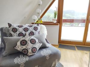 Cette chambre comprend un canapé avec des oreillers et une fenêtre. dans l'établissement LOFT FOLK Apartament Zakopane, à Zakopane