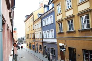 una calle de la ciudad con edificios y gente caminando por una calle en Apartament Warsaw Old Town - Piwna Street en Varsovia