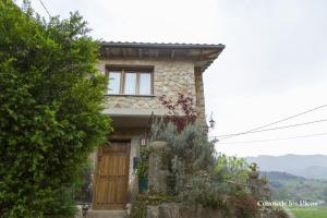 a stone house with a wooden door and trees at Vivienda Vacacional La Escribana - Casas de los Picos in El Mazo