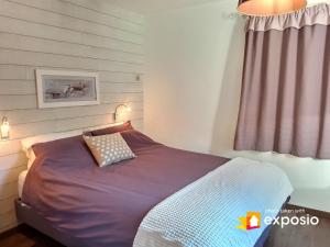 1 dormitorio con 1 cama con edredón morado y ventana en Charmant appartement de 50m2 pour 2 personnes - terrasse et balcon en Courchevel