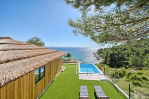 una casa con piscina y techo de paja en Kamp Lunga +, en Jezera