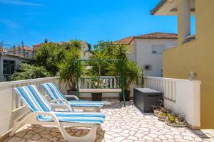 two lounge chairs on a balcony with a grill at Apartments Kasalo in Trogir