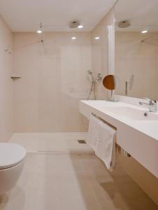 
a white toilet sitting next to a bath tub in a bathroom at Hotel Los Robles in Gandía
