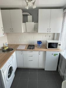 a kitchen with white cabinets and a washer and dryer at Апартаменты LUX в центре. Ярослава Мудрого 72 (97й квартал) in Kryvyi Rih