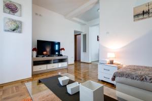 a white bedroom with a bed and a tv at Apartments Horizont in Budva