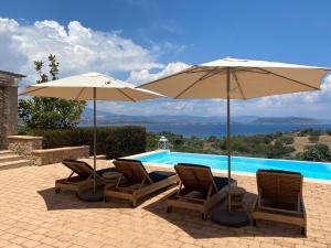 two chairs and umbrellas next to a swimming pool at Big Blue Villa Porto Heli in Porto Heli