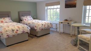 a bedroom with two beds and a table and windows at Argyll House Bed and Breakfast in Westleton
