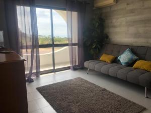 a living room with a couch and a large window at Apartamento em cima da praia - Carvoeiro - Algarve in Poço Partido