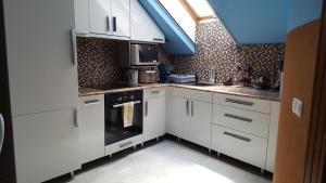 een keuken met witte kasten en een fornuis met oven bij Paris-Lux. in Hajdúszoboszló