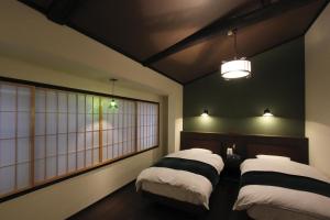 two beds in a room with black walls and windows at Kiyomizu Birodo-an in Kyoto