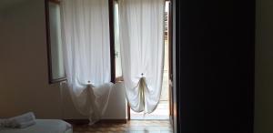 eine offene Tür zu einem Schlafzimmer mit weißen Vorhängen in der Unterkunft La Casetta nel cuore del Parco in Locana