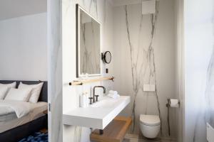 a white bathroom with a sink and a bed at Zlata Ladjica Boutique Hotel in Ljubljana
