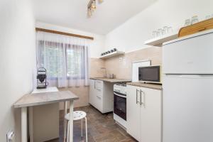 eine Küche mit weißen Schränken, einem Tisch und einem Waschbecken in der Unterkunft Familia nyaraló 16 in Balatonmáriafürdő