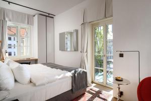 a white bedroom with a bed and windows at Zlata Ladjica Boutique Hotel in Ljubljana