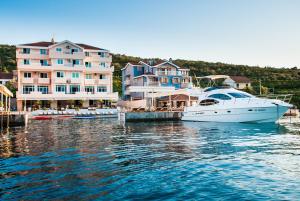 un bateau blanc amarré dans un port avec des maisons dans l'établissement Apartments Adeona, à Tivat