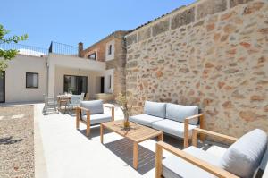 un patio con divani, tavoli e un muro di mattoni di Sa Vicaria a Santa Eugenia