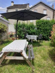 una mesa de picnic y una sombrilla en un patio en Gîte de Kerezenn, en Fougerolles