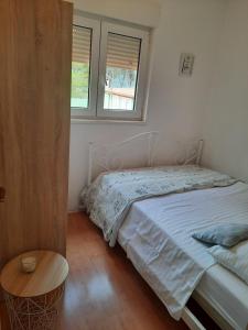 ein Schlafzimmer mit einem Bett, einem Tisch und zwei Fenstern in der Unterkunft Apartments Jurić - Zablaće in Zablaće