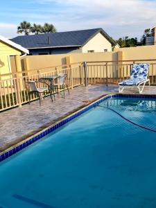 a swimming pool with a table and chairs next to a fence at 36 frere road shelly beach , margate in Margate