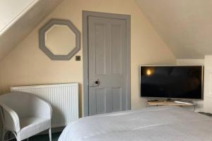 a bedroom with a bed and a tv and a chair at The Annex Keith Self Catering WiFi Private Parking bkng in Keith