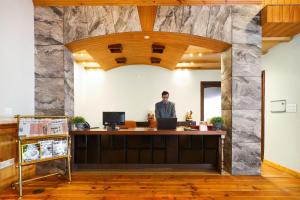 Ein Mann steht an einem Schreibtisch in einem Büro mit einer Steinmauer. in der Unterkunft Regenta Resort & Spa Mashobra in Shimla