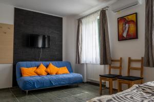 Pension Max Valtice في فالتيس: أريكة زرقاء مع وسائد برتقالية في غرفة النوم