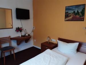 um quarto de hotel com uma cama e uma cadeira e uma televisão em Hotel Gasthof Zur Krone em Beerfelden