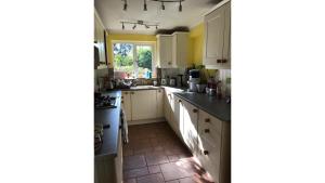 una cucina con armadietti bianchi e una finestra di Camelot Retreat - Tor View a Glastonbury