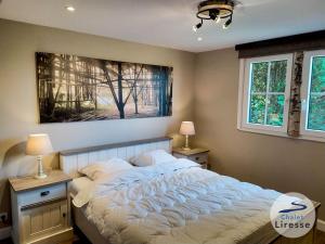 ein Schlafzimmer mit einem großen Bett und einem Gemälde an der Wand in der Unterkunft Chalet la Liresse in Rochehaut