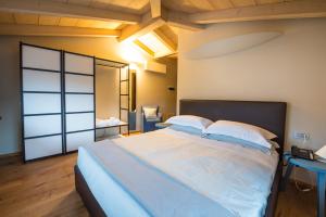 1 dormitorio con 1 cama grande con sábanas y almohadas blancas en Hotel Aqua Crua, en Barbarano Vicentino