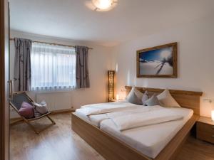 - une chambre avec un grand lit et une chaise dans l'établissement Ferienwohnung Eberharter, à Hart im Zillertal
