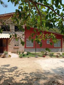 a red house with a tree in front of it at Pousada Villa Aurora in Serra Negra