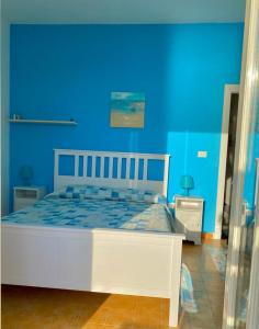 a bedroom with a white bed with a blue wall at Appartamento Lamù in Santa Maria di Castellabate