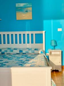 a bedroom with a bed with a blue wall at Appartamento Lamù in Santa Maria di Castellabate