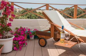 una silla y una botella de vino en un balcón con flores en Tal-Karmnu Entire house with private heated pool and jacuzzi en Kirkop