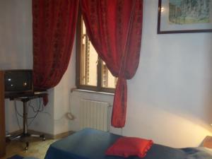 um quarto com uma cama e uma janela com cortinas vermelhas em Il Pretoriano em Roma