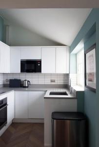 a kitchen with white cabinets and a black stool at Central Hastings, Stylish-Luxe, Seaside Apartment. in Hastings