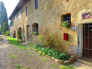un edificio de ladrillo con una puerta y plantas al lado en Il Mandorlo di Monteriggioni en Monteriggioni