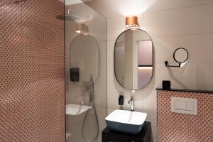 a bathroom with a toilet, sink, mirror and bath tub at Boutique Hotel Stanserhof in Stans