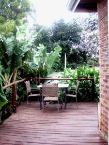 una mesa y sillas en una terraza de madera en Duvet & Crumpets, en Pietermaritzburg