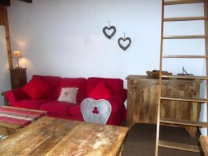 un soggiorno con divano rosso e cuori appesi al muro di Mayens de l'Ours MOUNTAIN & CENTER apartments by Alpvision Résidences ad Agettes