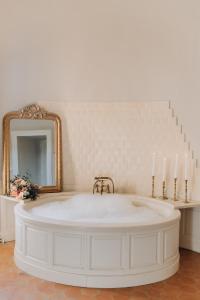 a bathroom with a tub with a mirror and candles at Château de la Cour Senlisse in Senlisse