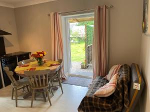 una sala da pranzo con un tavolo, un divano e una porta di Milkwood Cottage a Corwen