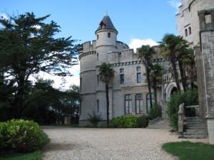 an old castle with palm trees in front of it at Park Village Océlandes in Saint-Julien-en-Born