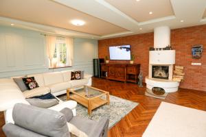 salon z kanapą i kominkiem w obiekcie Iseroase House Deluxe w mieście Pobiedna