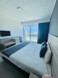 a bedroom with a large bed with a large window at Hotel VIU57 in Mellieħa