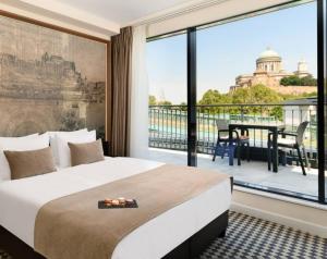 a hotel room with a bed and a large window at Grand Hotel Esztergom in Esztergom