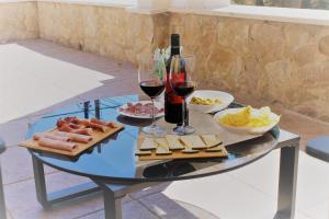 una mesa de cristal con vino, queso y copas de vino en villa mimoses en Palmanyola